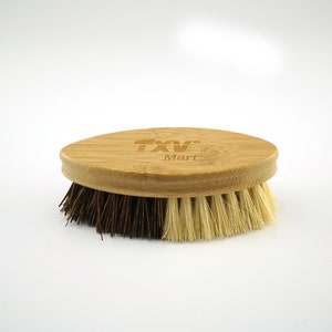 May include: A wooden brush with a brown and white bristle brush head. The handle is oval shaped and made of bamboo. The handle has the text "TXV Mart" engraved on it.