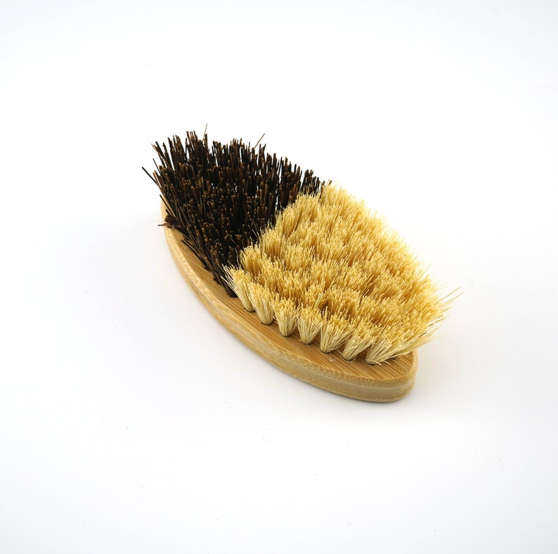 May include: A wooden-handled brush with two sides. One side has natural bristles and the other side has black bristles.