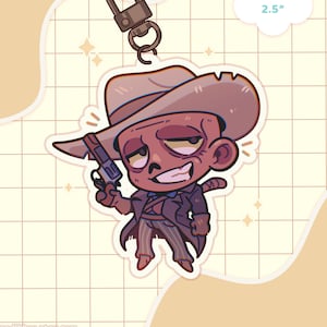 Könnte beinhalten: Ein Cartoon-Ghul, der einen braunen Cowboyhut und einen schwarzen Anzug trägt und eine Pistole hält. Der Ghul lächelt und hat eine braune Hautfarbe. Der Anhänger ist 6,35 cm groß.