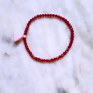 May include: A red beaded bracelet with a pink tassel.
