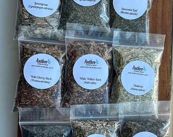 May include: A collection of 15 small clear plastic bags filled with dried herbs. Each bag has a white circular label with the name of the herb and its botanical name. The labels also include the company name "Anthro" and website address "www.AnthroHerbs.com".