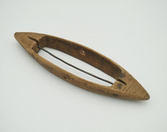 May include: A wooden shuttle with a metal wire running through the centre. The shuttle is used for weaving.