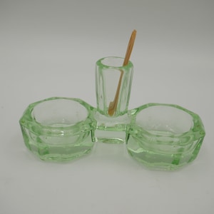 Könnte beinhalten: Eine grüne Glassalzdose mit drei Fächern. Das mittlere Fach enthält einen kleinen Holzstab.