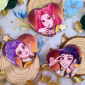 Peut inclure: Épingles en forme de cœur avec des illustrations de style anime de femmes aux cheveux roses et violets. Les épingles sont disposées sur des tranches de bois et décorées de feuilles d'or, de fleurs et d'étoiles. Les épingles ont un fond dégradé.