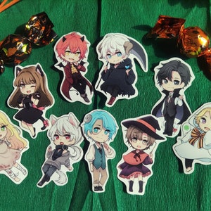 May include: Ten colorful cartoon character stickers featuring different characters in Halloween costumes. The stickers are on a green background with orange and gold candy wrappers.