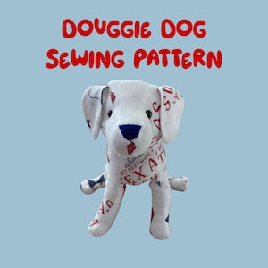 May include: A stuffed dog sewing pattern labeled "Douggie Dog Sewing Pattern." The dog is white with blue and red accents, and the fabric is printed with the word "Texas." The dog has floppy ears and a blue nose.