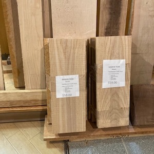 May include: Two stacks of wood planks labeled "Harbor Teak Hardwood Craft Pack" with a price of $59.00. The wood planks are light brown and have a natural wood grain.