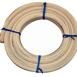 May include: A coiled roll of thin, light-colored wooden strips, bound with blue twine. The strips are tightly wound, forming a circular shape. The wood has a natural, unfinished appearance.
