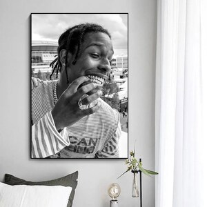Puede incluir: Fotograf&iacute;a en blanco y negro de una persona sonriendo con una rejilla de oro. La persona lleva una camisa a rayas con la palabra "San" visible.