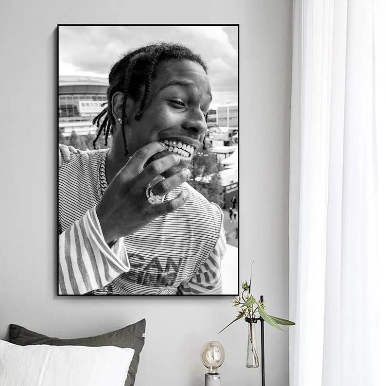 Puede incluir: Fotograf&iacute;a en blanco y negro de una persona sonriendo con una rejilla de oro. La persona lleva una camisa a rayas con la palabra "San" visible.