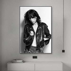 Puede incluir: Fotografía en blanco y negro de una persona que lleva una chaqueta de cuero negra con cierre de cremallera. La persona mira hacia un lado y tiene el pelo corto y oscuro.