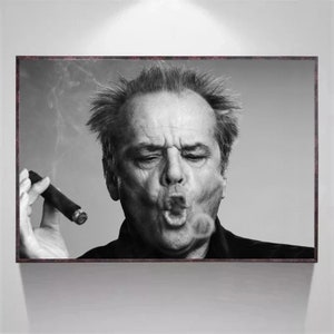 Puede incluir: Retrato en blanco y negro de un hombre con una expresión seria, soplando humo de un cigarro. El hombre lleva una chaqueta oscura y tiene una calvicie incipiente.