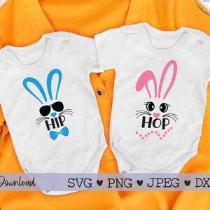 May include: Two white onesies with bunny faces and the words "Hip Hop" printed on them. The onesies are laid out on a yellow surface with a basket of Easter eggs in the background.
