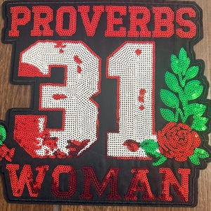 May include: A black fabric patch featuring red sequined text that reads PROVERBS 31 WOMAN. The large number 31 is white with red sequin accents. A green sequined leafy branch and a red sequined rose are positioned to the right of the number.