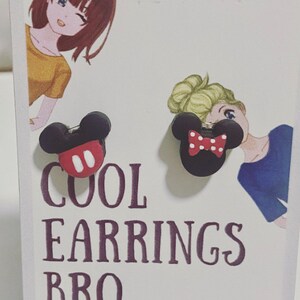 May include: A pair of black and red Mickey Mouse and Minnie Mouse earrings. One earring has a red bow with white polka dots. The other earring has a red face with two white circles. The text "COOL EARRINGS BRO" is printed below the earrings.