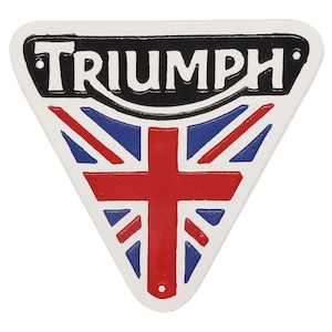 May include: A white, triangular Triumph logo with a black border and the word "TRIUMPH" in white. The logo features a Union Jack design in red, white, and blue.
