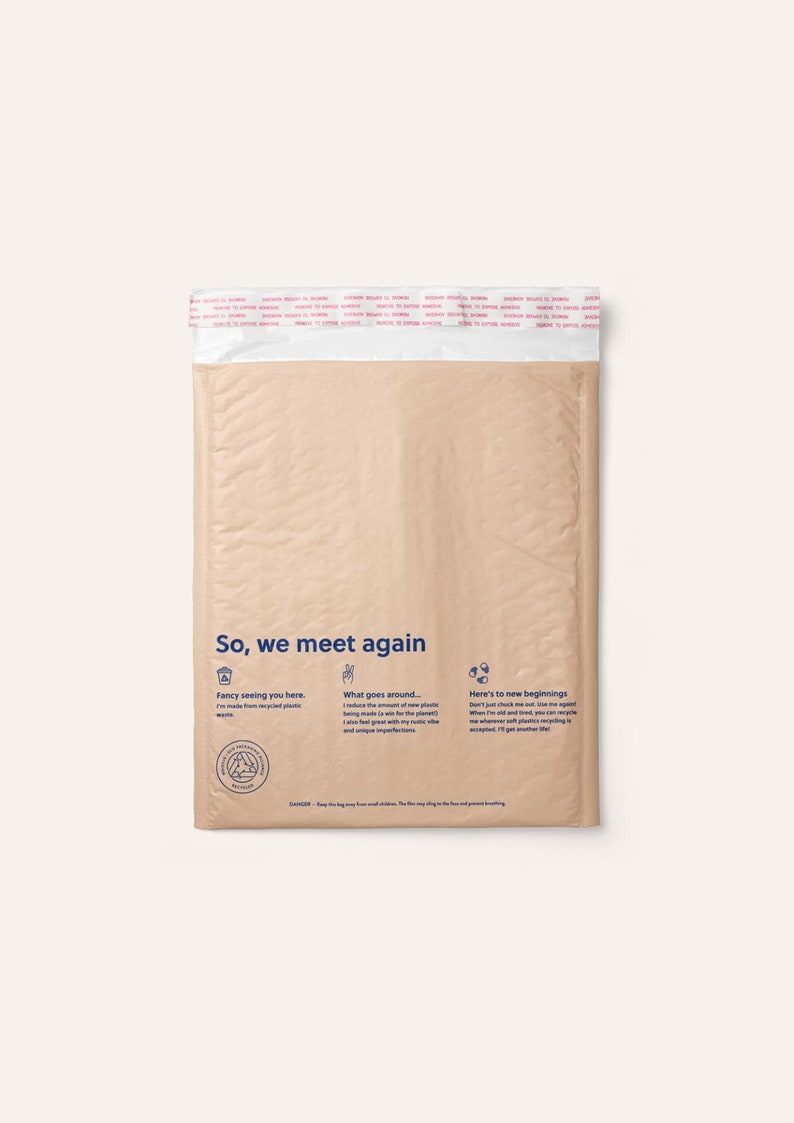 May include: A tan-coloured, rectangular padded shipping mailer made from recycled plastic. The front features the text 'So, we meet again' in blue, along with three icons and descriptive text about its recycled nature and instructions for reuse.