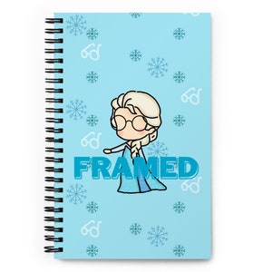 May include: A blue spiral notebook with a cartoon illustration of a girl with blonde hair wearing glasses and a blue dress. The girl is surrounded by snowflakes and glasses. The word "FRAMED" is written in blue letters below the girl.