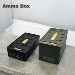 May include: Two ammo boxes, one black and one green, with a bullet silhouette and caliber printed on the front. The black box says "9mm" and the green box says ".223 REM".