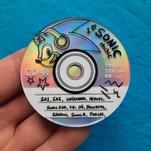 Può includere: Un CD-R olografico con Sonic the Hedgehog e la scritta "I Love Sonic Music". Il design del CD include il testo "SA1, SA2, Unleashed, Heroes, Sonic 3&K, CD, 06, Frontiers, Shadow, Sonic R, Forces."