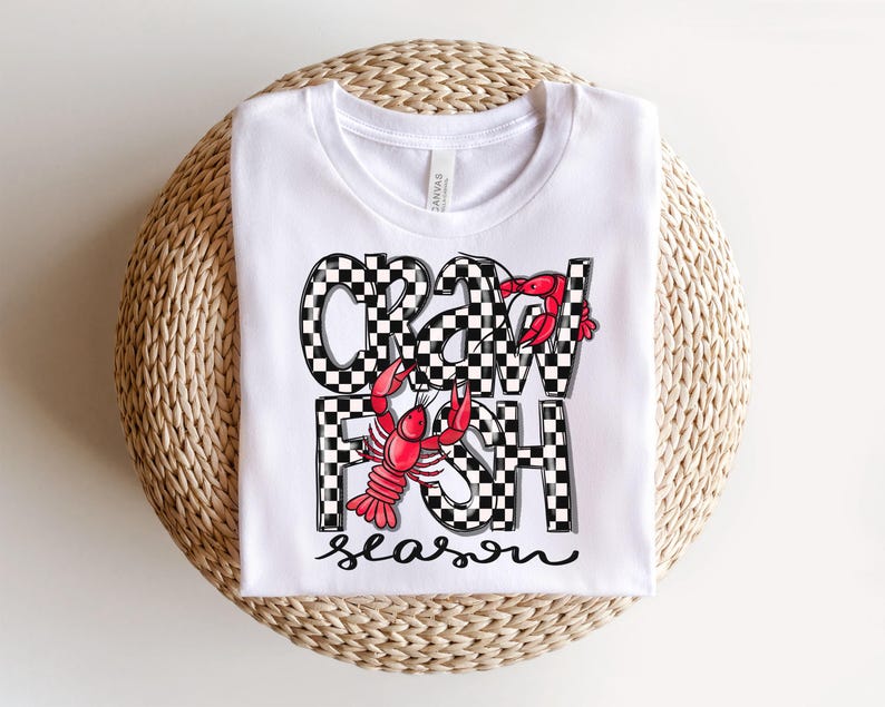 May include: White toddler t-shirt featuring a crawfish design. The crawfish are red and the text is black and white checkered. The text on the shirt says 'Crawfish Season'.