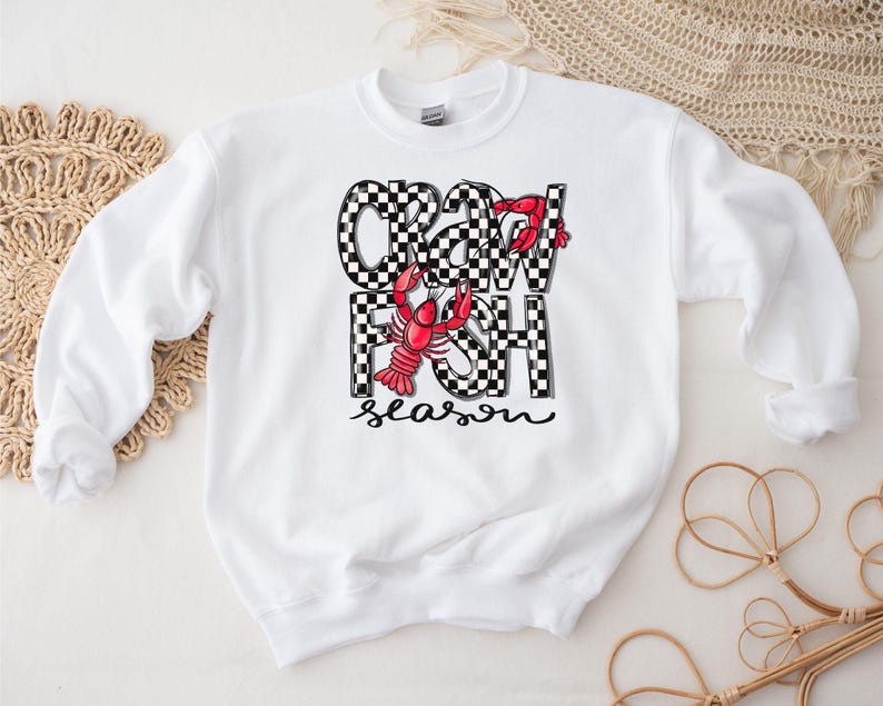 May include: White sweatshirt with a black and white checkered design that says "Crawfish Season" with a red crawfish illustration.