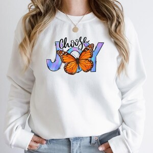 May include: White sweatshirt with a colorful butterfly graphic and the text "Choose Joy" printed on the front.