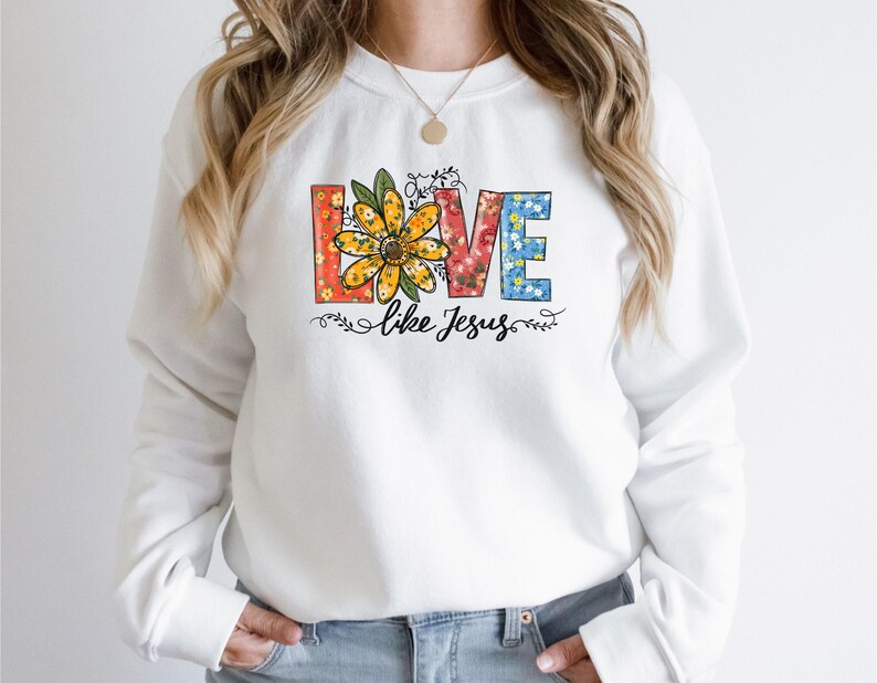 May include: White sweatshirt with a floral design that spells out "LOVE" with the words "like Jesus" underneath.