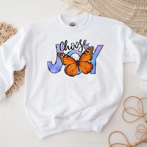 May include: White sweatshirt with a colorful butterfly graphic and the text "Choose Joy" printed on the front.