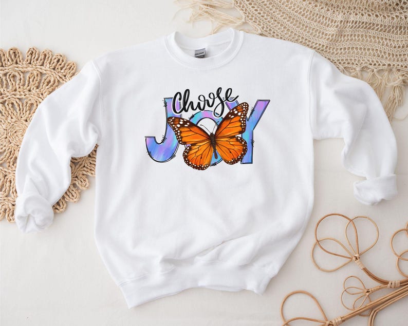 May include: White sweatshirt with a colorful butterfly graphic and the text "Choose Joy" printed on the front.