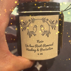 May include: A small black jar with a brown label that reads "Noir Un-hex Root Removal Healing & Protection 4 oz".
