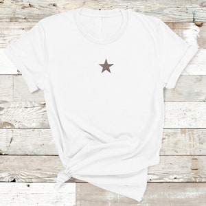 May include: White t-shirt with a brown star on the front.