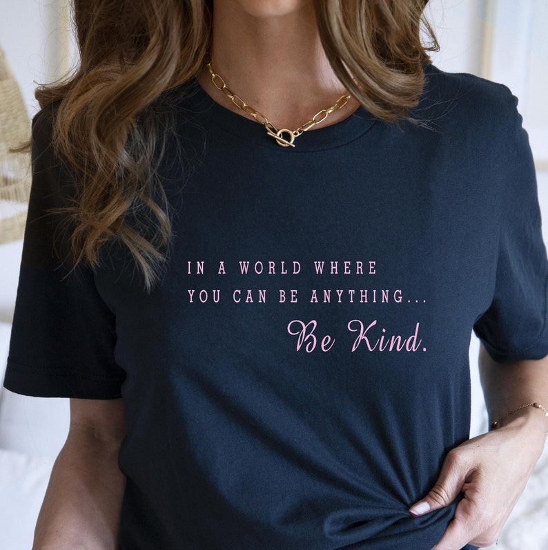 May include: A black t-shirt with the text "In a world where you can be anything... Be Kind." printed in pink.