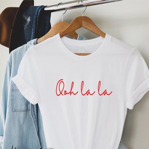 May include: White t-shirt with the phrase "Ooh la la" written in red cursive script.