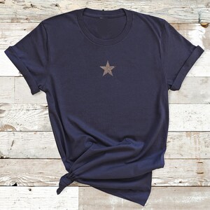 May include: A navy blue t-shirt with a gold glitter star on the front.