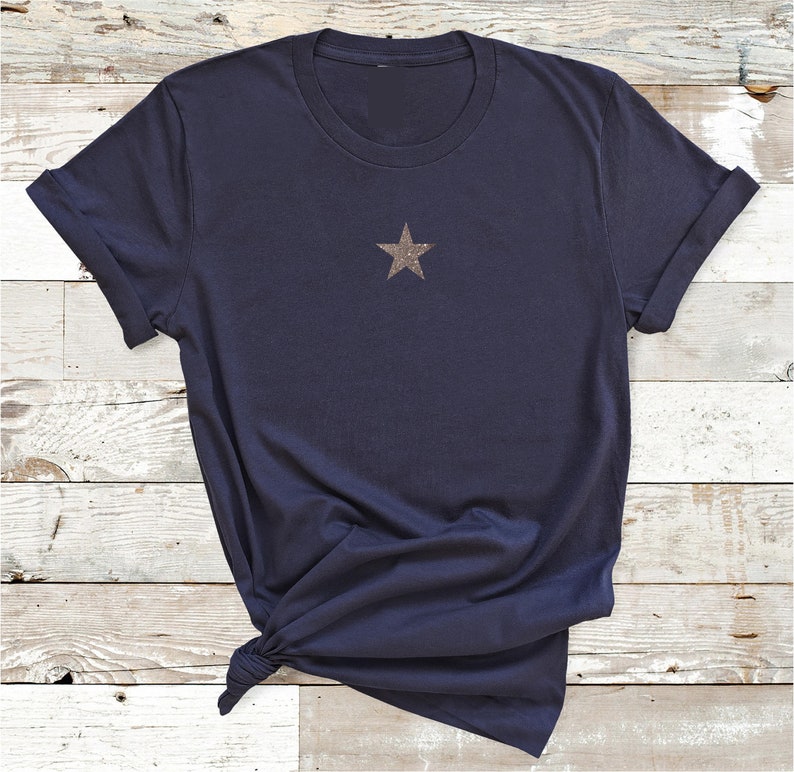 May include: A navy blue t-shirt with a gold glitter star on the front.
