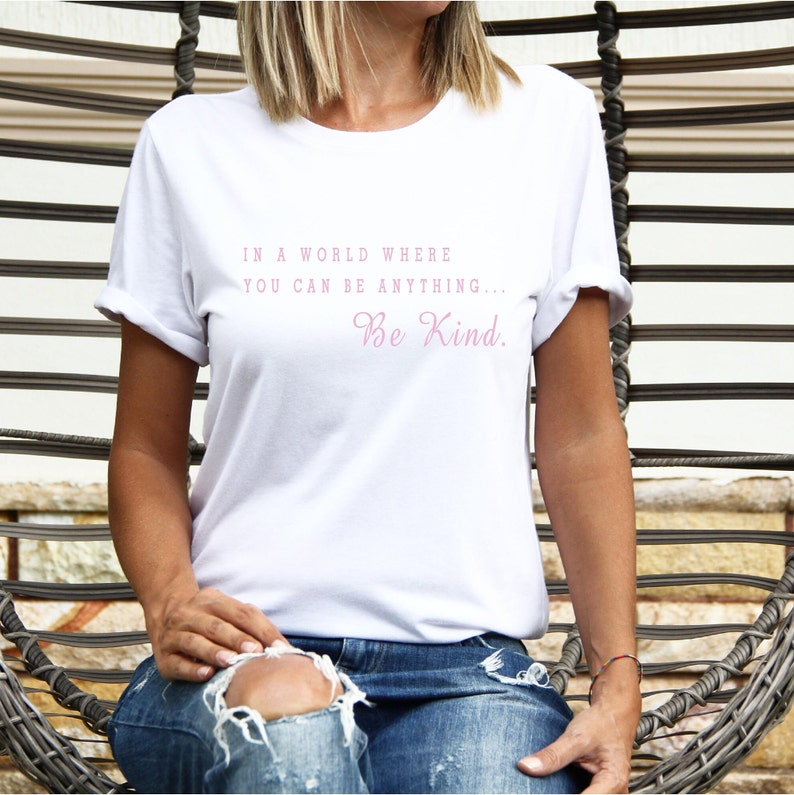 May include: White t-shirt with the text "In a world where you can be anything... Be Kind." printed in pink.