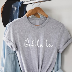 May include: A gray t-shirt with the text "Ooh la la" written in white cursive script.