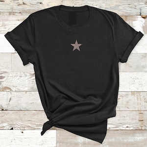 May include: A black t-shirt with a small, glittery gold star on the front.