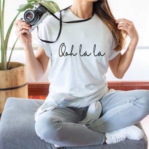 May include: A white t-shirt with the text "Ooh la la" written in black cursive script.