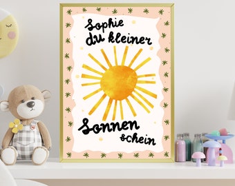 May include: A pink and white framed print with a yellow sun and the text "Sophie du kleiner Sonnenschein" in black.