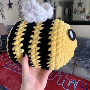 Pode incluir: Uma abelha de pel&uacute;cia redonda com listras amarelas e pretas, asas brancas e fofas e um olho pequeno. A abelha feita &agrave; m&atilde;o &eacute; macia e aconchegante, perfeita como brinquedo infantil ou decora&ccedil;&atilde;o de quarto.