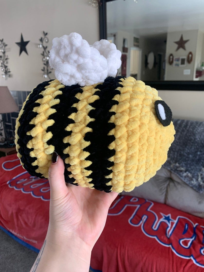 Pode incluir: Uma abelha de pel&uacute;cia redonda com listras amarelas e pretas, asas brancas e fofas e um olho pequeno. A abelha feita &agrave; m&atilde;o &eacute; macia e aconchegante, perfeita como brinquedo infantil ou decora&ccedil;&atilde;o de quarto.
