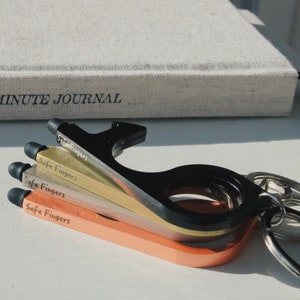 May include: Four multi-colored keychain tools with the text "Safe Fingers" on each. The tools are stacked on top of each other and have a ring attached to the top.