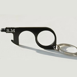 May include: Black metal keychain tool with a stylus, bottle opener, and two loops. The keychain has the initials "S.M." engraved on it.