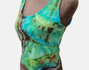 Pode incluir: Um top sem mangas com decote redondo, com um padrão tie-dye em tons de verde, azul e castanho. O tecido parece macio e a peça é exibida em um manequim. O design tie-dye cria um visual único e artístico.