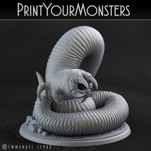 Puede incluir: Un modelo 3D impreso en gris de una criatura con forma de gusano con un ojo grande y garras afiladas. La criatura está enroscada en una posición defensiva sobre una base circular.