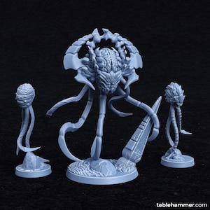 May include: A gray, 3D printed miniature of a creature with multiple tentacles and a brain-like head. The creature is standing on a base with a textured surface. Two smaller, gray, 3D printed miniatures of similar creatures are on bases to the left and right of the larger creature.