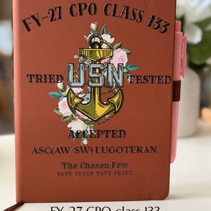 Könnte beinhalten: Ein rostfarbenes Notizbuch mit einer goldenen Ankergrafik und dem Text USN, umgeben von rosa Rosen. Der Einband enthält den Text FY-27 CPO CLASS 133, TRIED, TESTED, ACCEPTED, ASC(AW/SW) LUGOTERAN, The Chosen Few und NAVY CHIEF NAVY PRIDE.