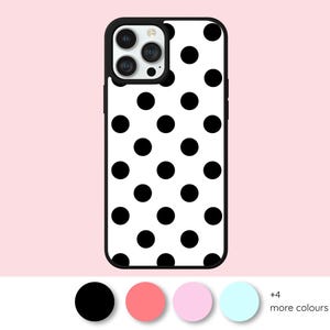 以下が含まれることがあります： 白と黒のドット柄の携帯電話ケース。ケースは黒い縁と、等間隔に配置された黒い円のある白い背景を持っています。携帯電話ケースは、明るいピンク色の背景に表示され、下に色のオプションがあります。